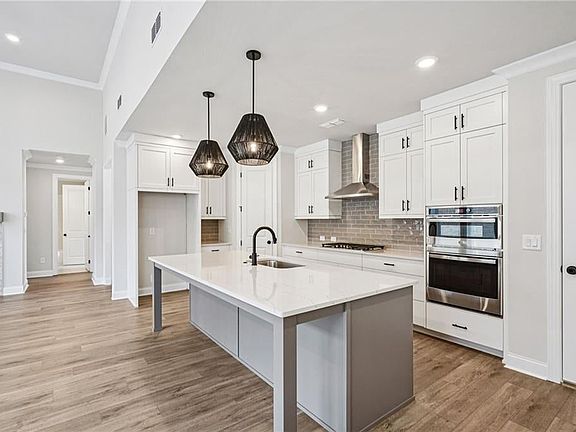 Kitchen featuring crown molding, white cabinetry, pendant lighting, tasteful backsplash, and an isla