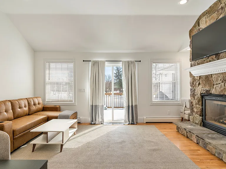 Stone Fireplace, TV Mount, Living Area, Deck Access, Large Windows, Bright Interior, Open Floor Plan.