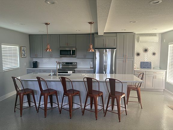 White counters with slight gray streaking make for a striking kitchen area. Features include new appliances, counter seating for 6, spacious work areas on either side of the oven and a dry bar area next to pantry cabinet great for entertaining.
