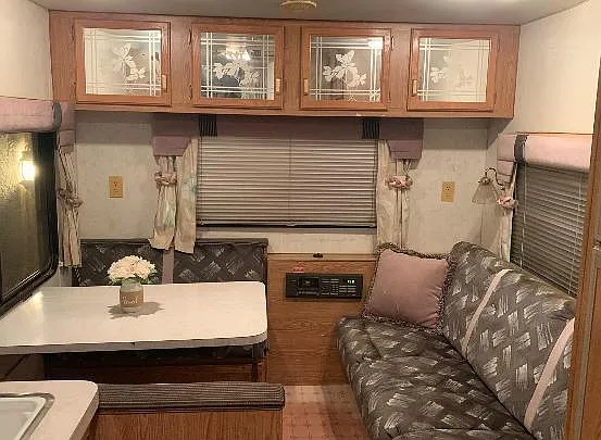 Compact RV-style sitting/dining nook with built-in cabinetry, cushioned bench seating, and a table for everyday meals.