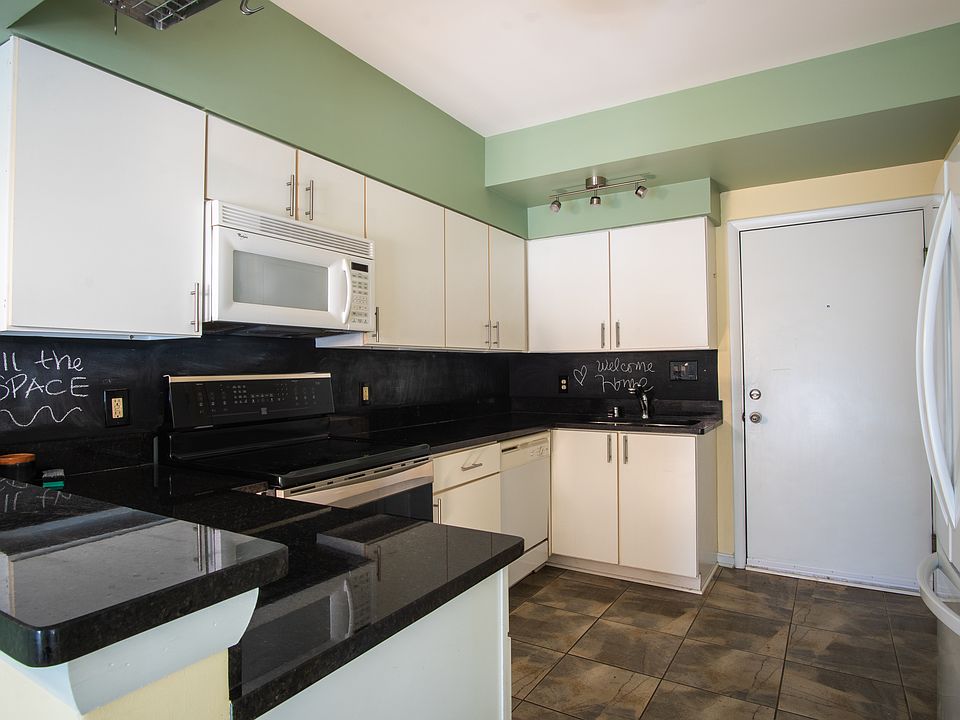 Spacious kitchen with modern appliances, washer and drier, tile floors, and granite countertops