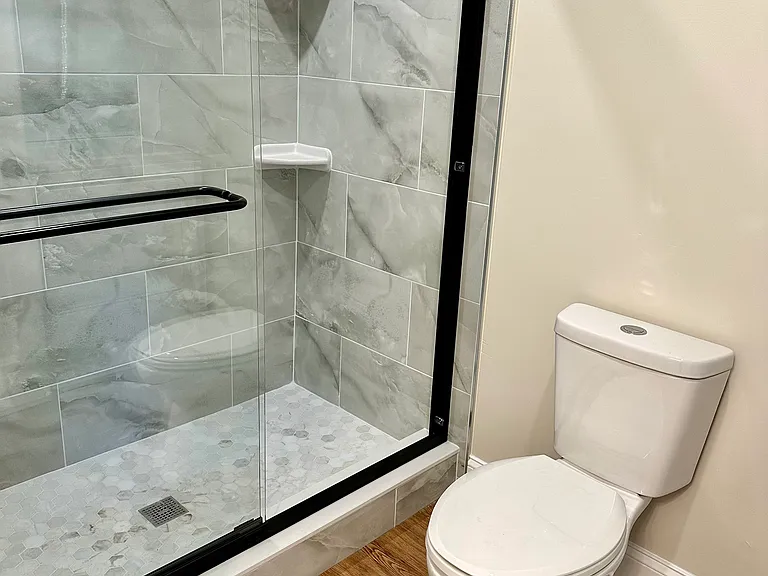 Walk-in shower featuring floor-to-ceiling tile, a frameless sliding glass door, and built-in corner shelves_combining style, comfort, and functionality.