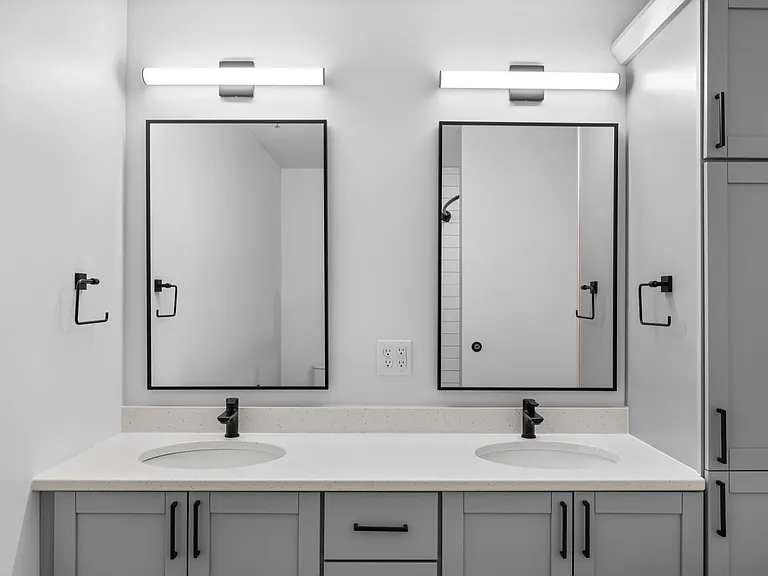Modern bathroom showcasing a sleek double vanity with black fixtures, elegant mirrors, and ample storage. Modern bathroom showcasing a sleek double vanity with black fixtures, elegant mirrors, and ample storage.