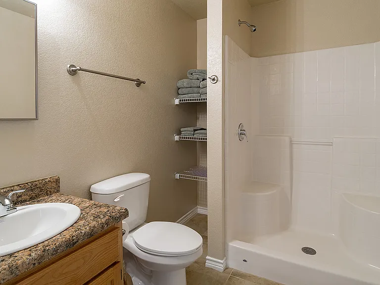 The master bath of a Phase 2 apartment home has a step-in shower and plenty of storage