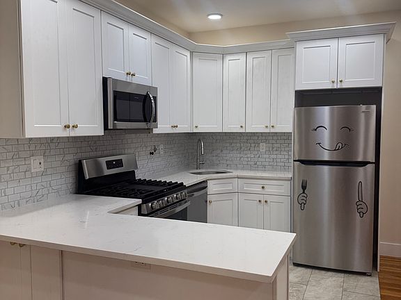 Fully renovated kitchen with white shaker cabinets, quartz countertops, and stainless steel appliances including a dishwasher.