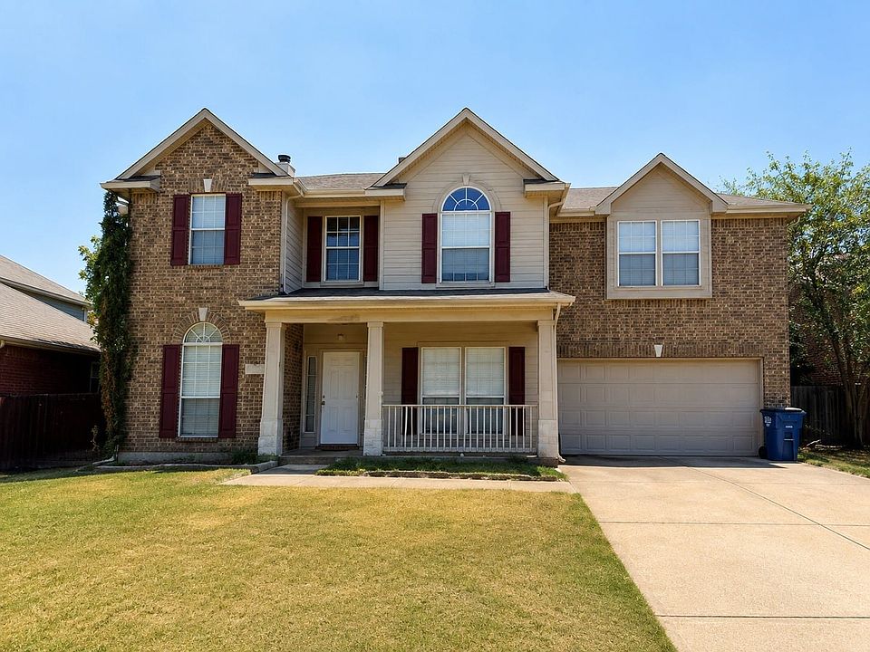 Brick and siding facade, covered front porch with railing, arched window accent, and an integrated two-car garage