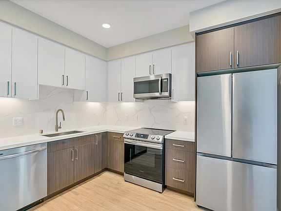 This full kitchen has a large sink, French-door fridge, dishwasher, microwave, and a stovetop oven.