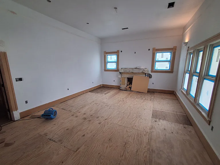 Living room looking east from bedroom. All new double paned windows. Brick mantle will be repaired and digital fireplace installed.
