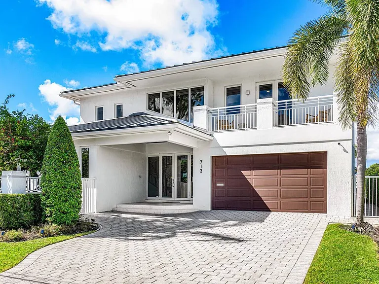Step into elegance with a grand entryway framed by lush greenery and sophisticated architecture.