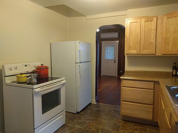 Kitchen with archway to living room at center and doorway to bedroom on the left and doorway to mudroom behind.