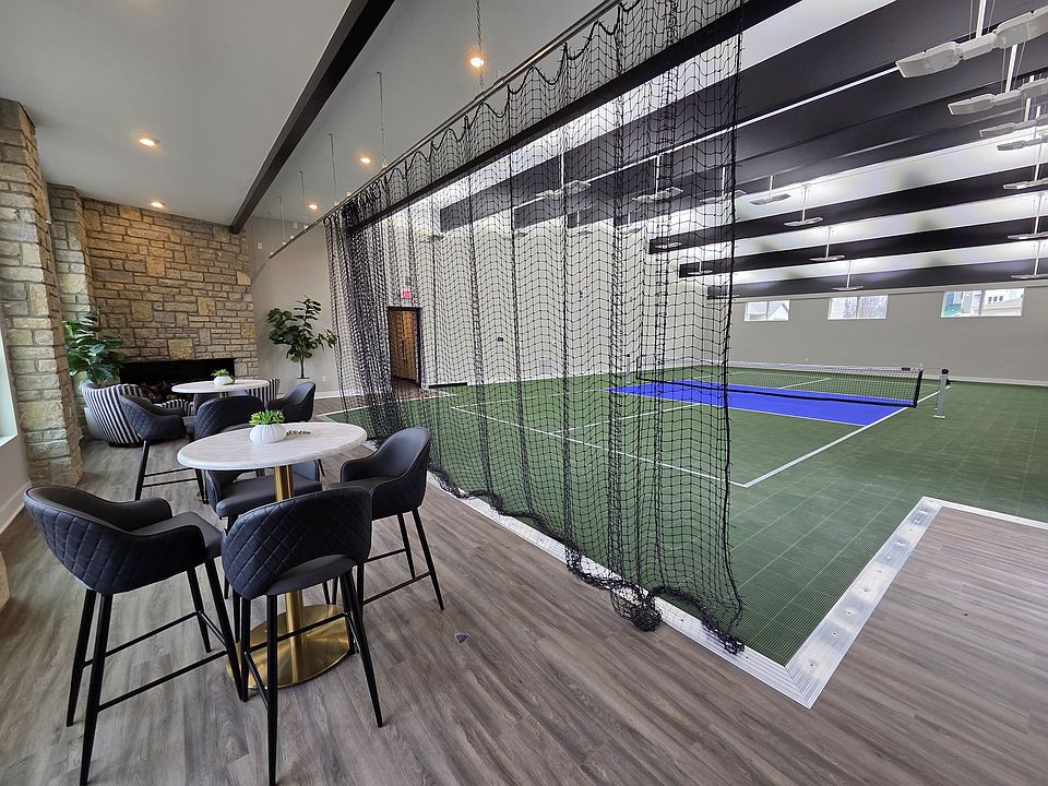 Indoor pickleball court with nearby seating and fireplace.