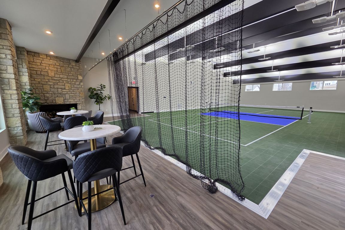 Indoor pickleball court with nearby seating and fireplace.