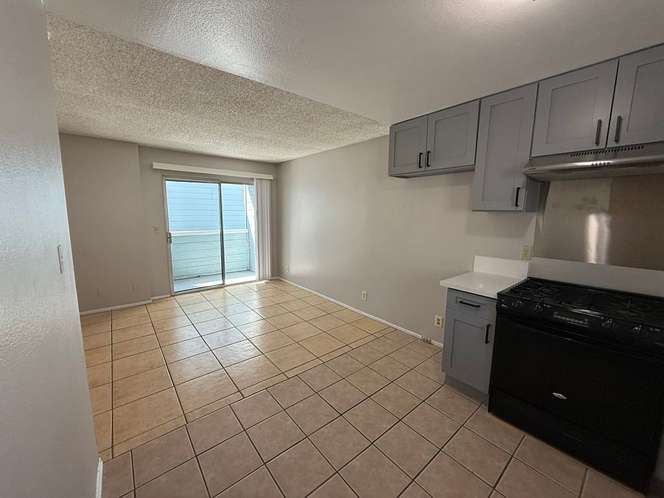 Brightly lit unit with newly renovated kitchen with grey shaker cabinets and white quartz countertop.