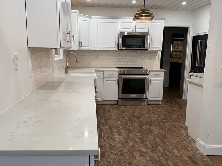 Spacious kitchen with quartz countertops and brick floors.