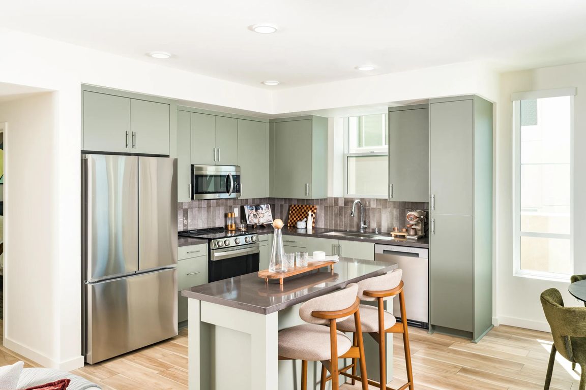 Kitchen and dining space with warm wood cabinetry, quartz surfaces, and expansive windows framing hillside views and natural light.