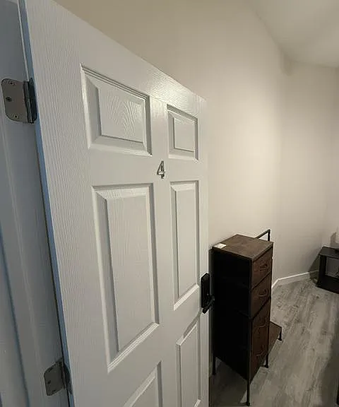 Private room with wood-look flooring and space for a dresser or work setup, with easy access from the hallway.