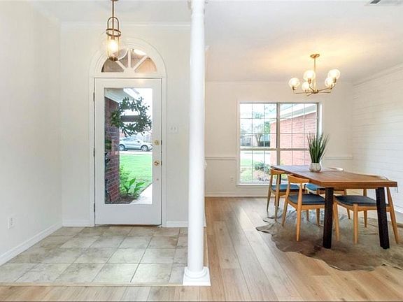 Foyer featuring decorative columns, crown molding, an inviting chandelier, and light hardwood / wood-style flooring