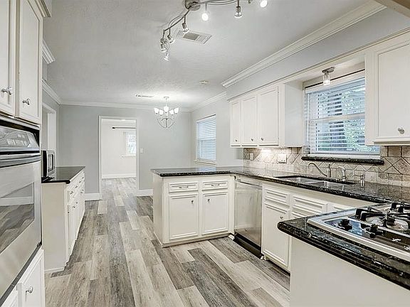 Track lighting electric oven and gas cooktop in the kitchen looking toward the breakfast room.