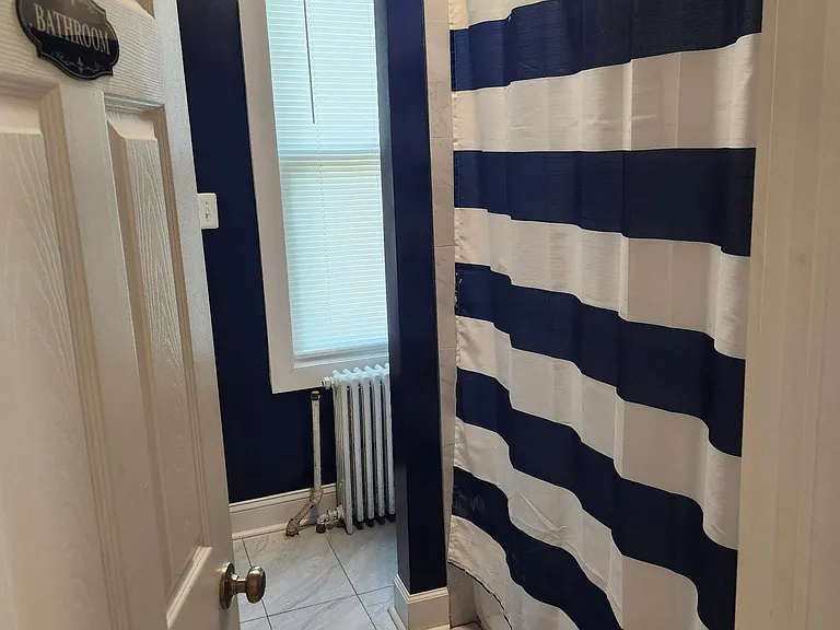 Full bathroom with tiled flooring, shower/tub with curtain, and a window for ventilation and natural light.
