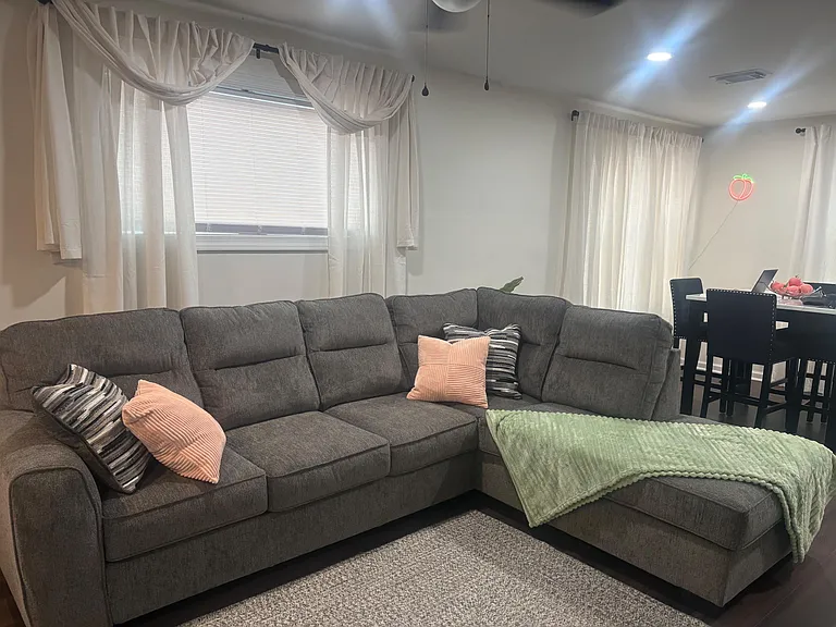 Open living area with a large sectional, soft carpet flooring, and nearby dining spaceideal for relaxing or hosting.