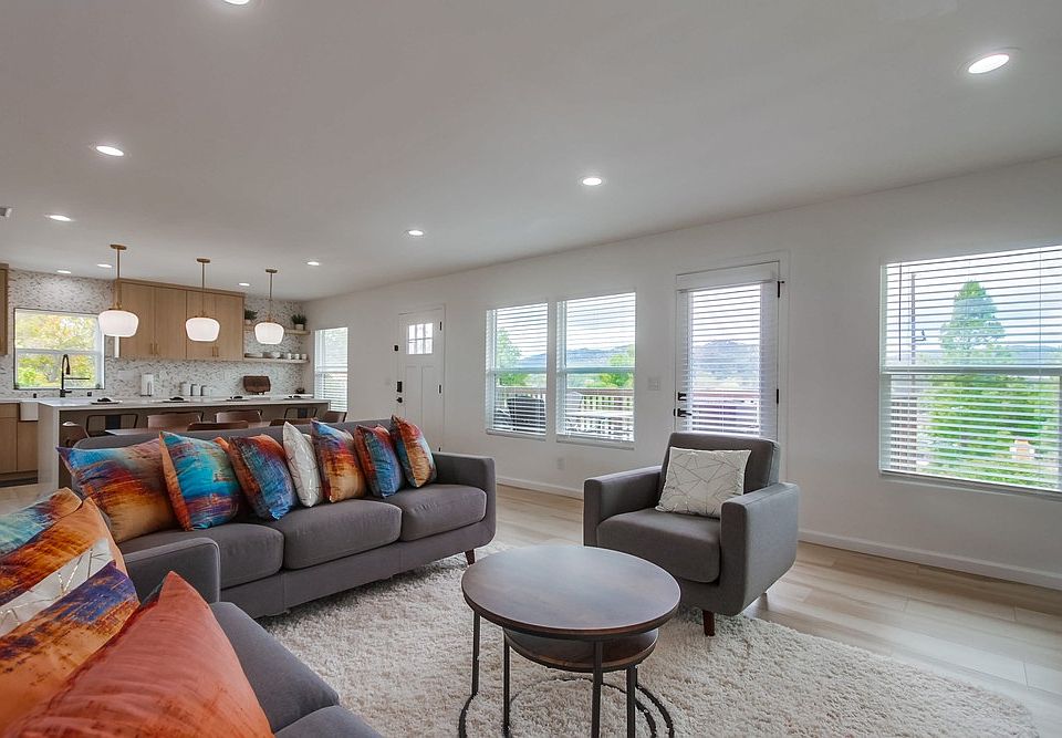 Relax in the spacious living room featuring comfortable couches, a 70-inch TV, and oversized windows that fill the space with natural light while showcasing the beautiful views.