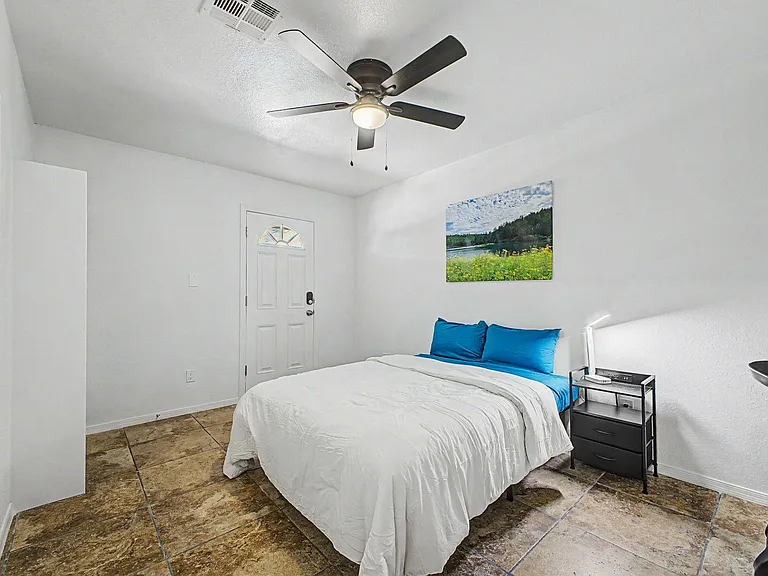 Private bedroom with a full bed, ceiling fan, and convenient nightstand, plus durable tile flooring for easy upkeep.
