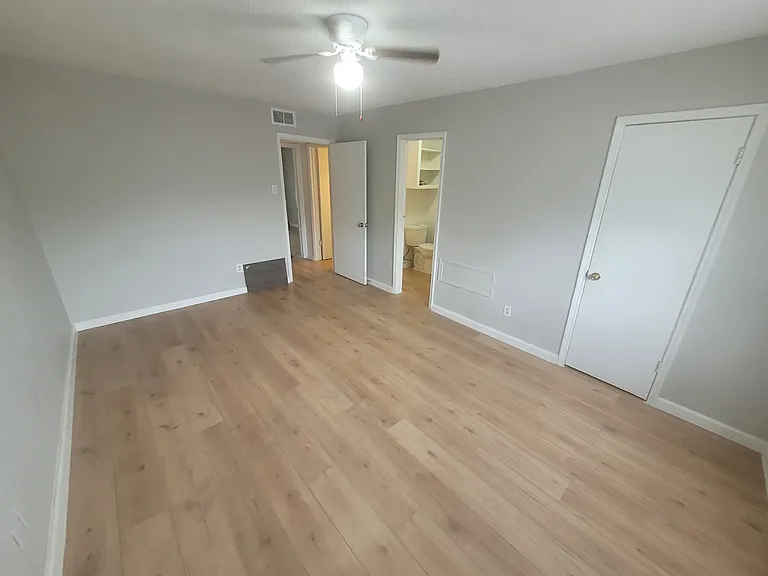 Inside view of (alley-facing) upstairs bedroom to the right of the stairs, one closet (rightmost door) and entrance to shower/toilet