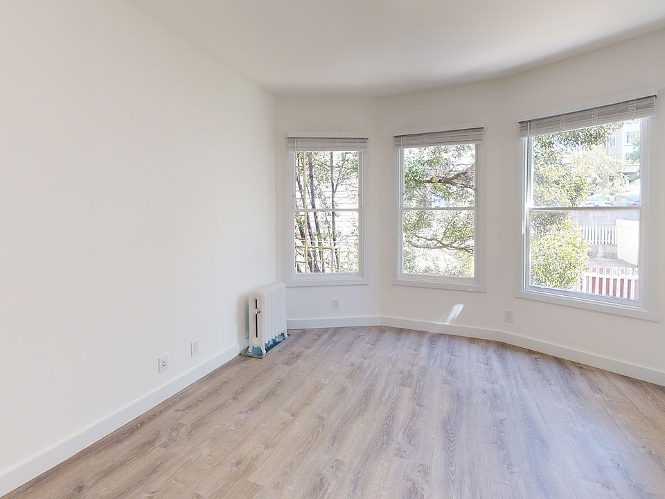 Sunlit room with a large window and wood-like flooring