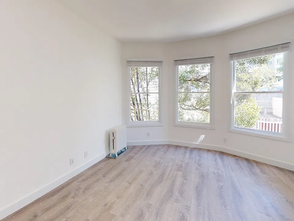 Sunlit room with a large window and wood-like flooring