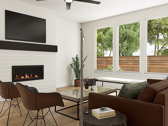 A cozy and modern living room with a fireplace, large windows overlooking a lush outdoor area, and c