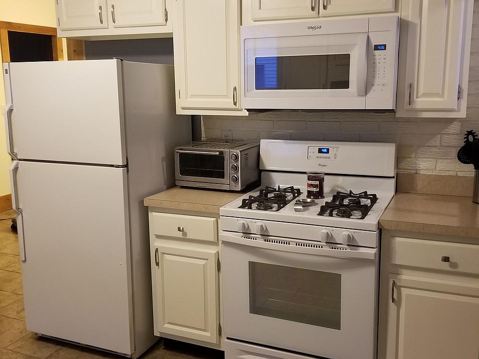 Half of the kitchen shown with refrigerator, microwave, gas range (appliances provided with unit except toaster oven), new countertops