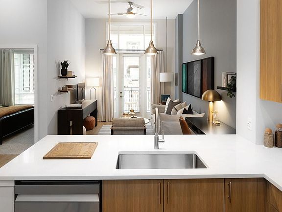 Kitchen and living area with oak cabinetry, white quartz countertops, and pendant lighting