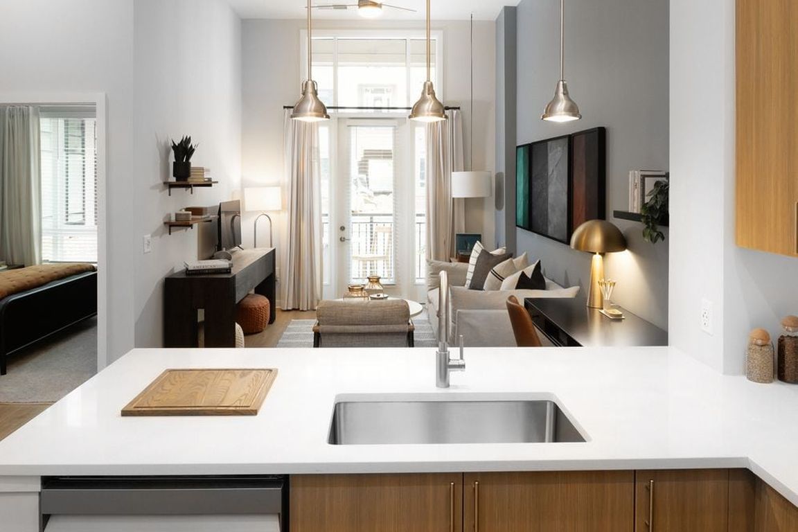 Kitchen and living area with oak cabinetry, white quartz countertops, and pendant lighting