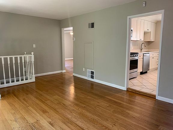 Living room with view of kitchen entry and hallway leading to bathroom 1 and bedroom 1 and 2.