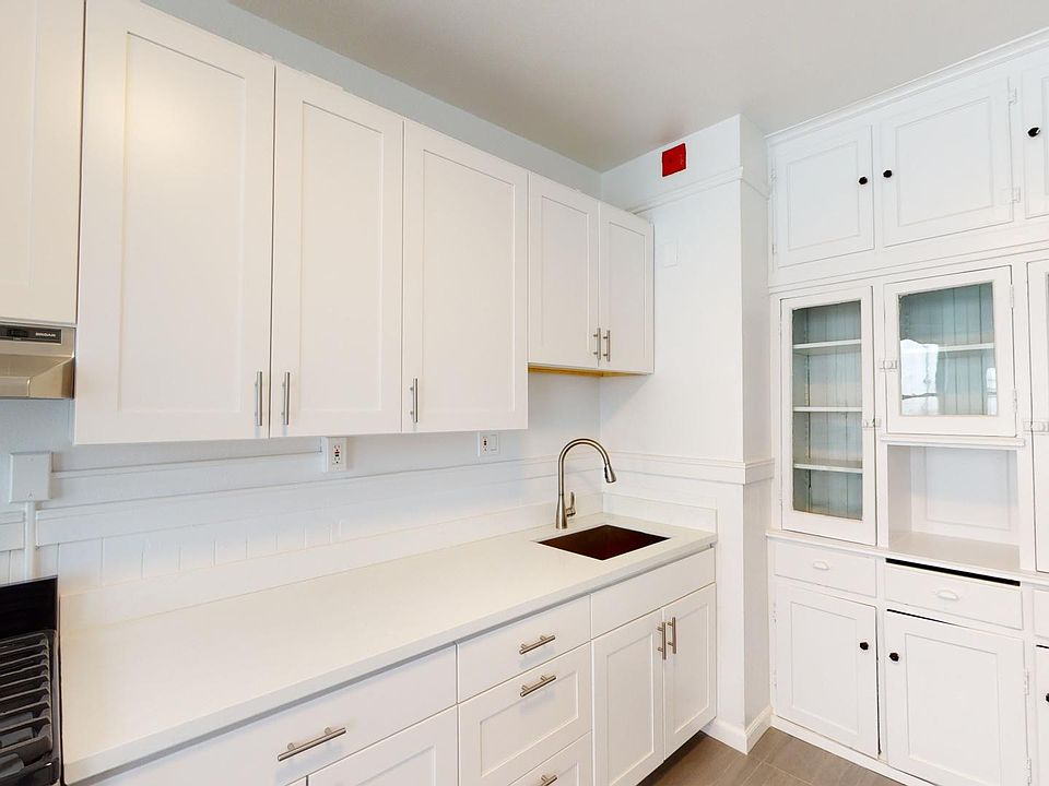 Kitchen featuring cabinets, a stainless steel sink, and a gas stove, with a glass-fronted cabinet for display
