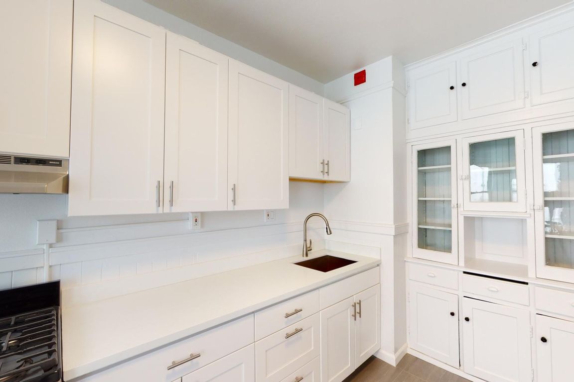 Kitchen featuring cabinets, a stainless steel sink, and a gas stove, with a glass-fronted cabinet for display