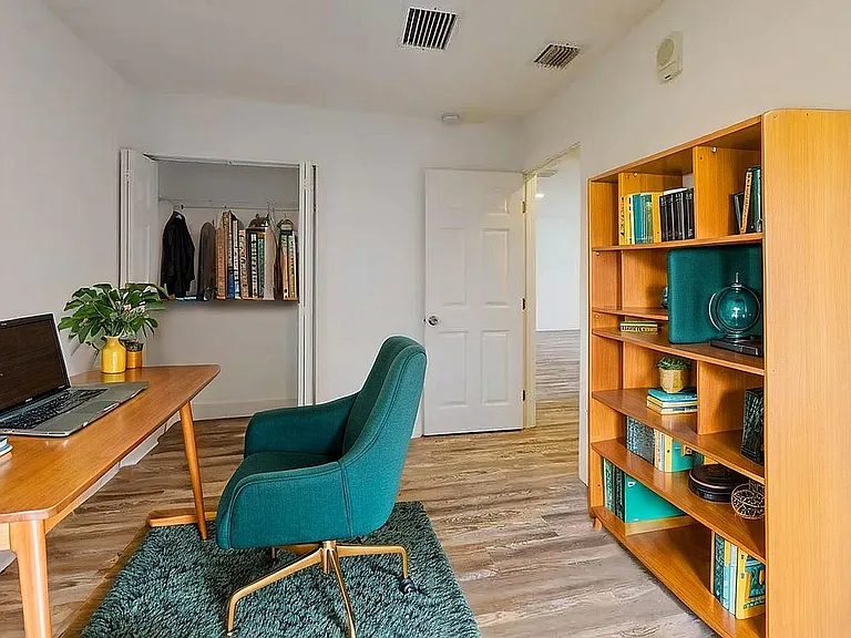 Inviting home office with modern decor, featuring a sleek wooden desk, stylish green chair, and a well-organized bookshelf. Perfect blend of functionality and elegance.