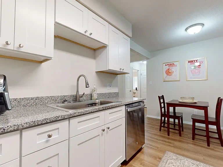Modern kitchen with sleek granite countertops, stylish white cabinetry, and cozy dining nook featuring elegant art decor. Modern kitchen with sleek granite countertops, stylish white cabinetry, and cozy dining nook featuring elegant art decor.