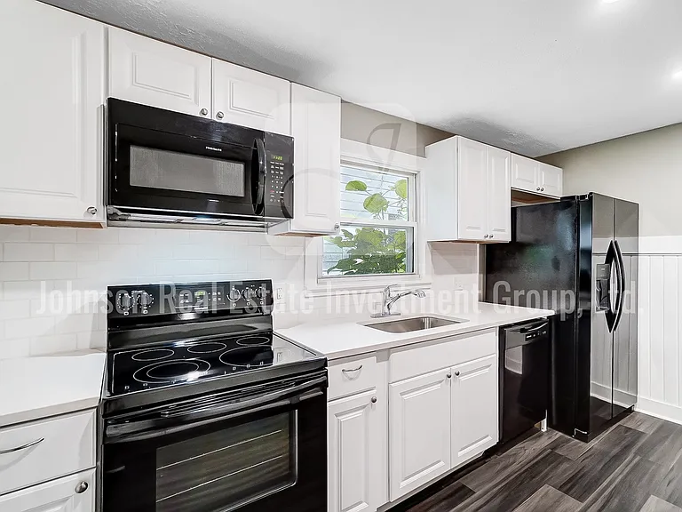 Stunning remodeled kitchen with black appliances and white quartz countertops!