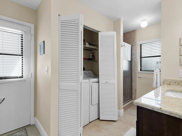 Washer dryer in guest bathroom with direct pool & lanai access.
