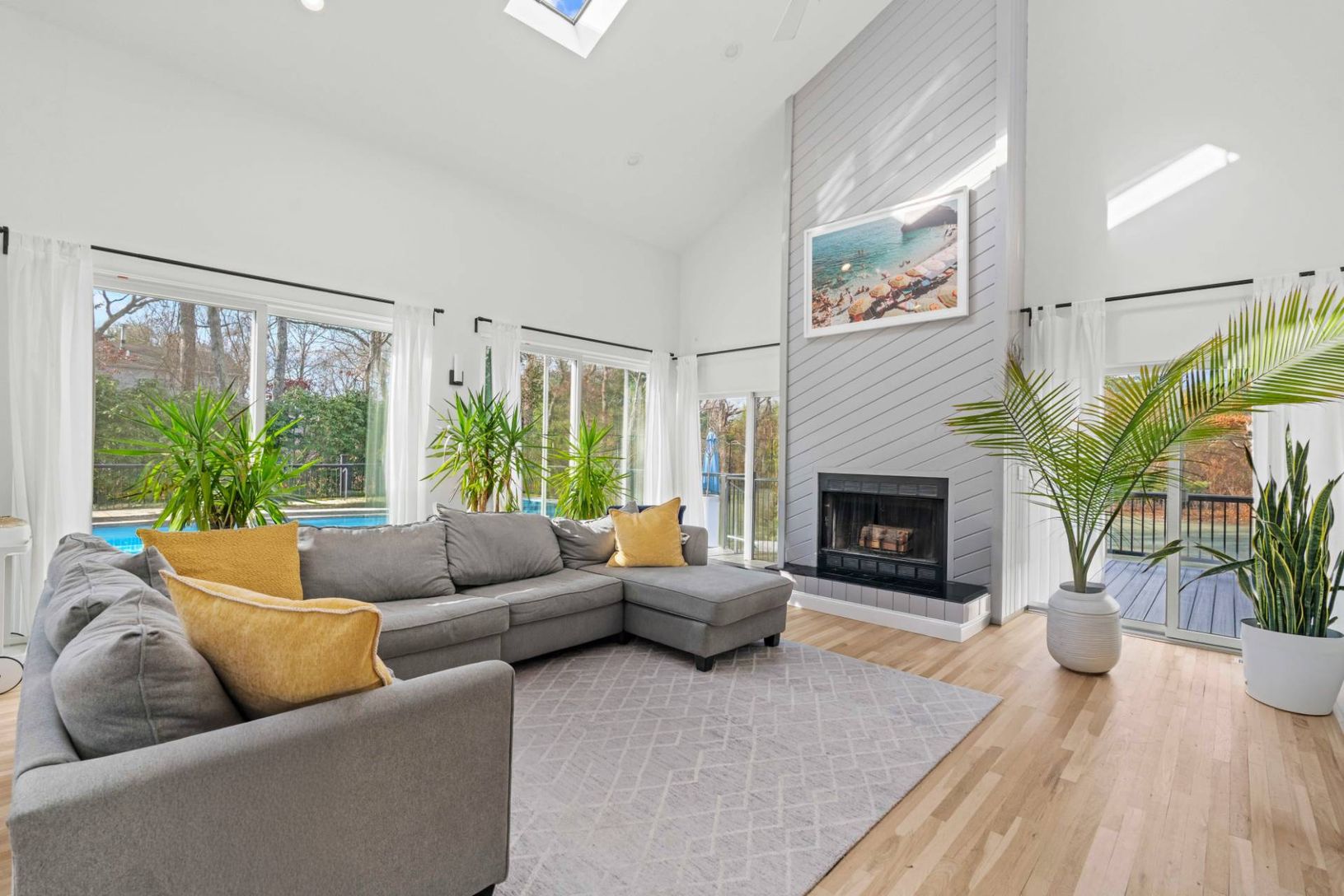 Great room featuring high vaulted ceiling, multiple skylights, beautiful oak floors, and fireplace