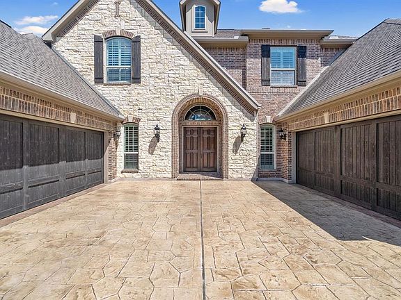 Impressive stone and brick exterior, stamped concrete driveway, wooden doors on both two car garages.