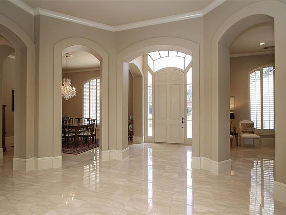 IMPRESSIVE ENTRY WITH 14 FT CEILINGS, CROWN MOLDING AND MARBLE FLOORS. The entry in the home shows all the gentle arch ways that from each room in the front of the house. The arched door and windows above complement the interior archways!