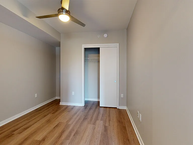 Spacious apartment bedroom with wood-style flooring.