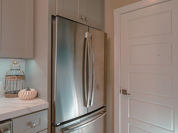The cabinet depth stainless steel French door refrigerator has a large capacity freezer/ice maker. Also visible in this photo is the door into the 1/2 bath.
