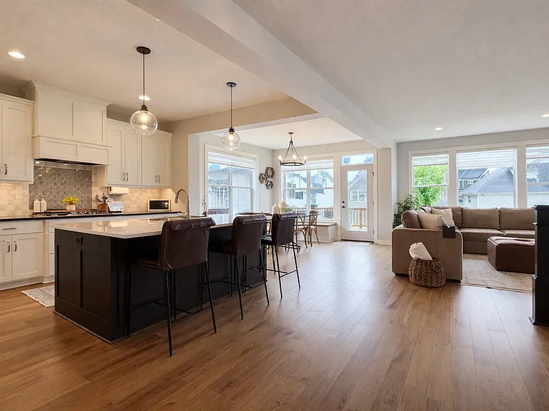 Open-concept kitchen and living area featuring a large island, modern cabinetry, and warm hardwood floors. Thoughtful layout flows effortlessly into the dining space and living room.