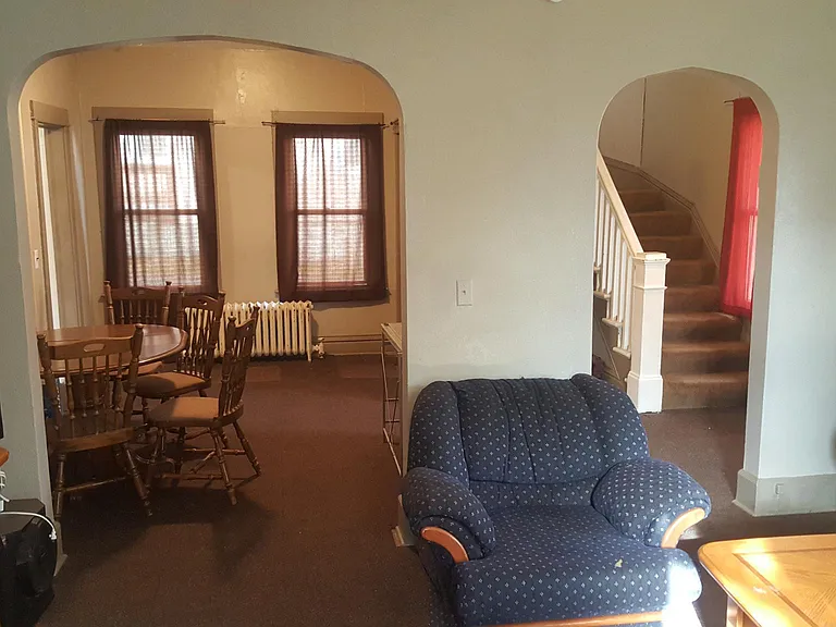 Living room with view of dining/sitting area and front door entry/stairs. (kitchen entry forward far left basement entry on right)
