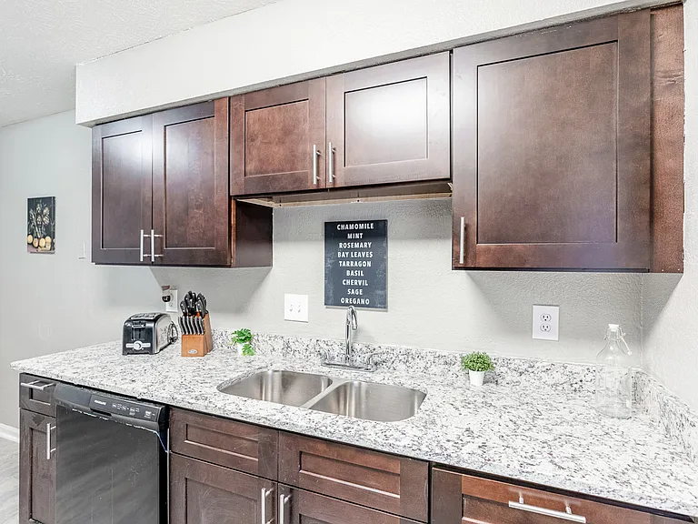 Gorgeous kitchen with granite countertops, cookware, toaster, utensils, and black appliances.