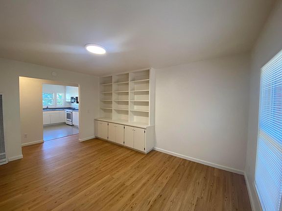 Large living room with built-in cabinetry and west-facing windows overlooking Strawberry Creek Park