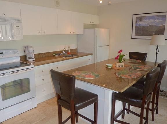 Complete kitchen with dining counter, microwave, stove and refrigerator.
